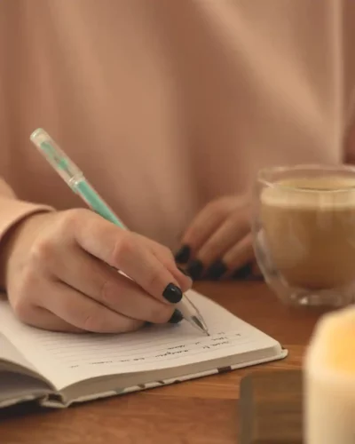 Camille Duroc écrivant dans un carnet avec un café, auteur culinaire de Cuisine Joie