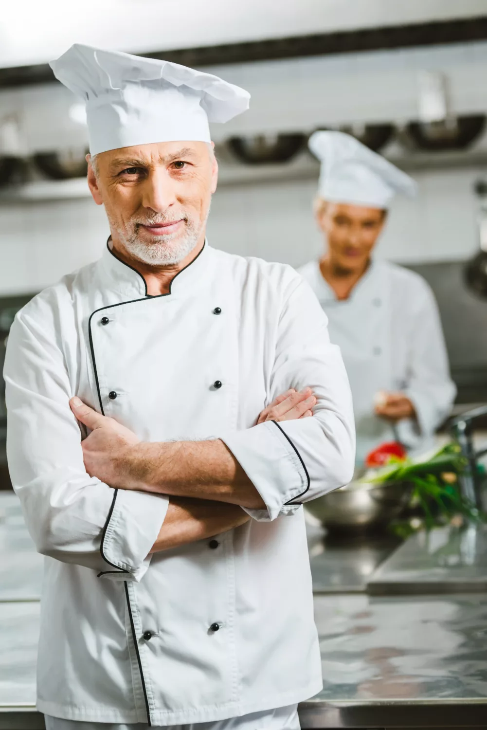 Portrait du chef Maxime Laurent en tenue blanche, bras croisés et souriant, incarnant confiance et convivialité culinaire.